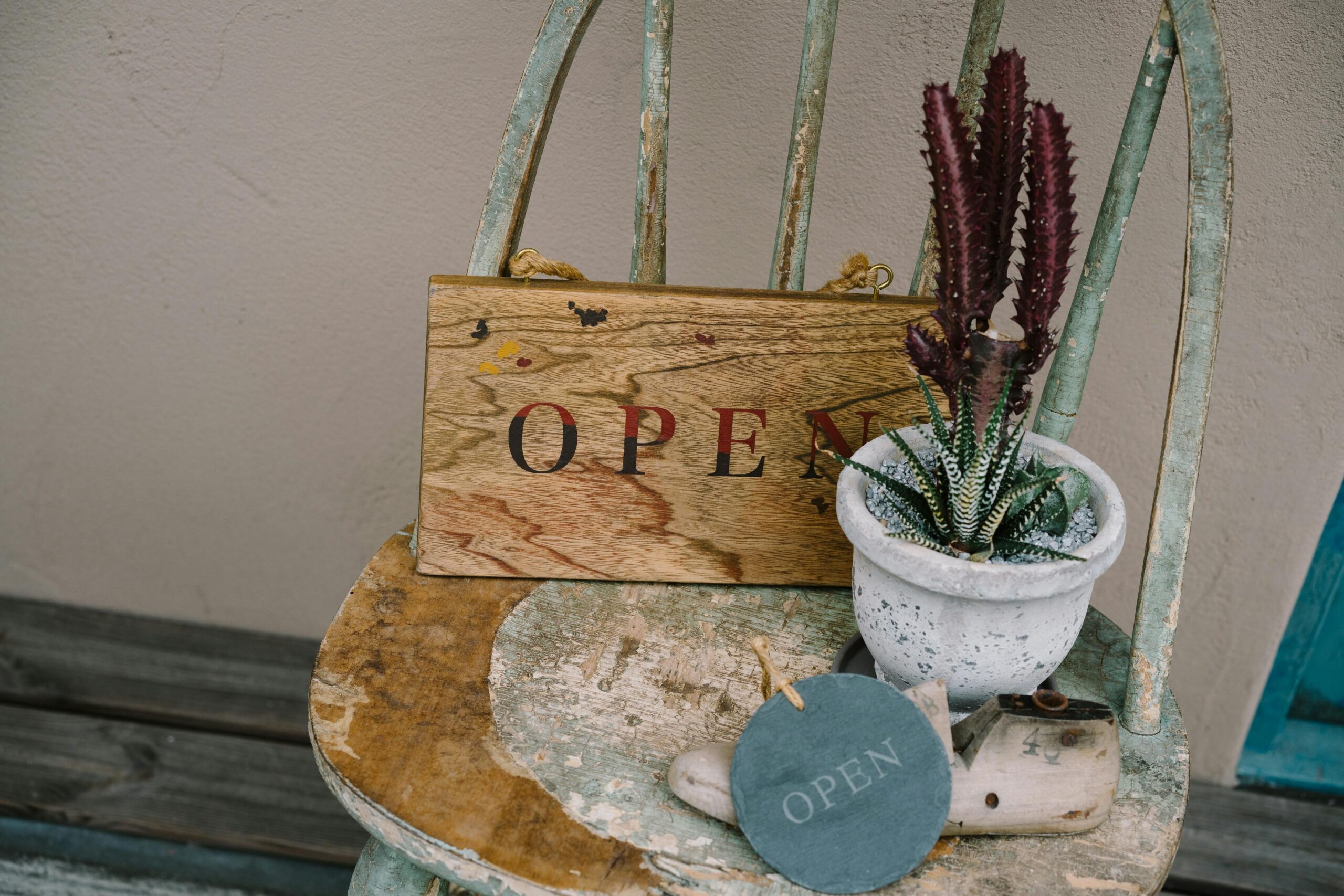 pexels photo 23962115 23962115 A vintage chair with an open sign, potted cactus, and rustic decor, creating a welcoming atmosphere.