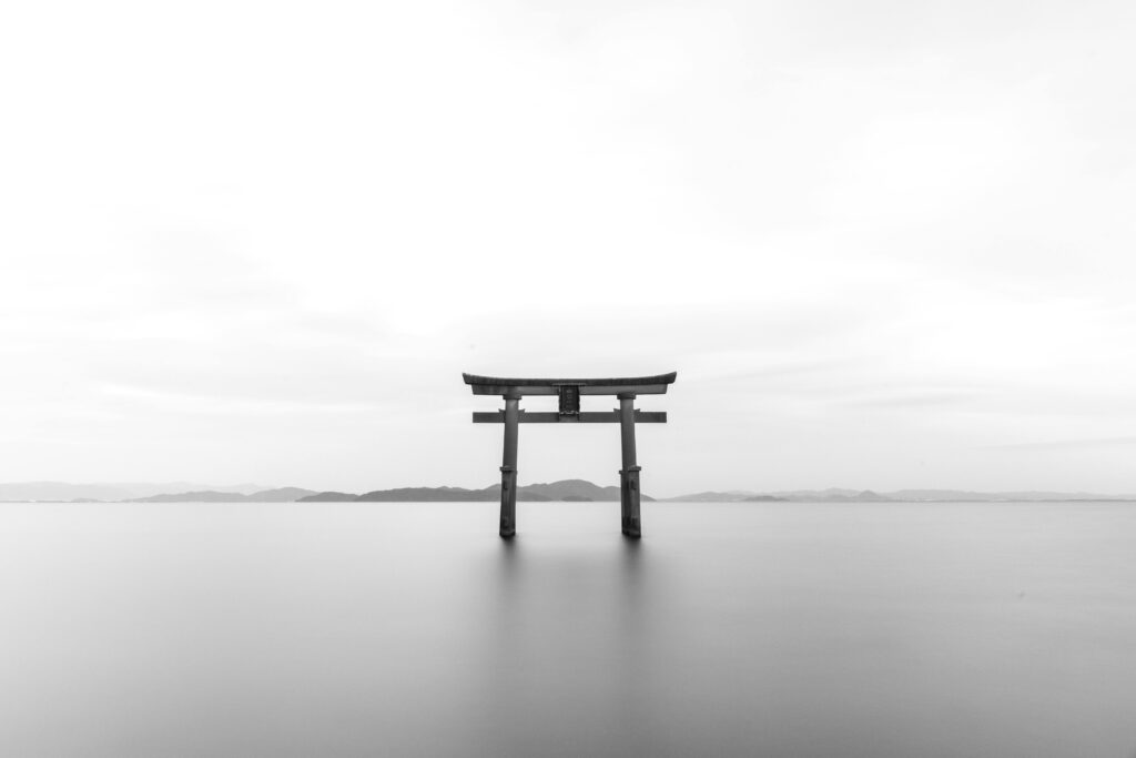 Japan: The Art of Kakeibo (Mindful Spending) Serene black and white image of a torii gate standing in calm waters, symbolizing tranquility.